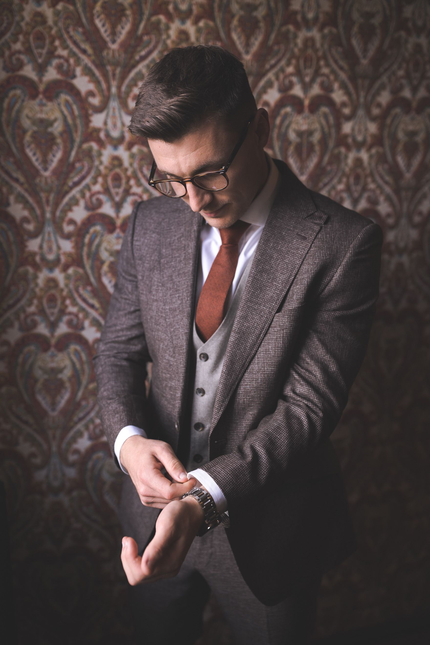 A man in a suit and tie is adjusting his watch.