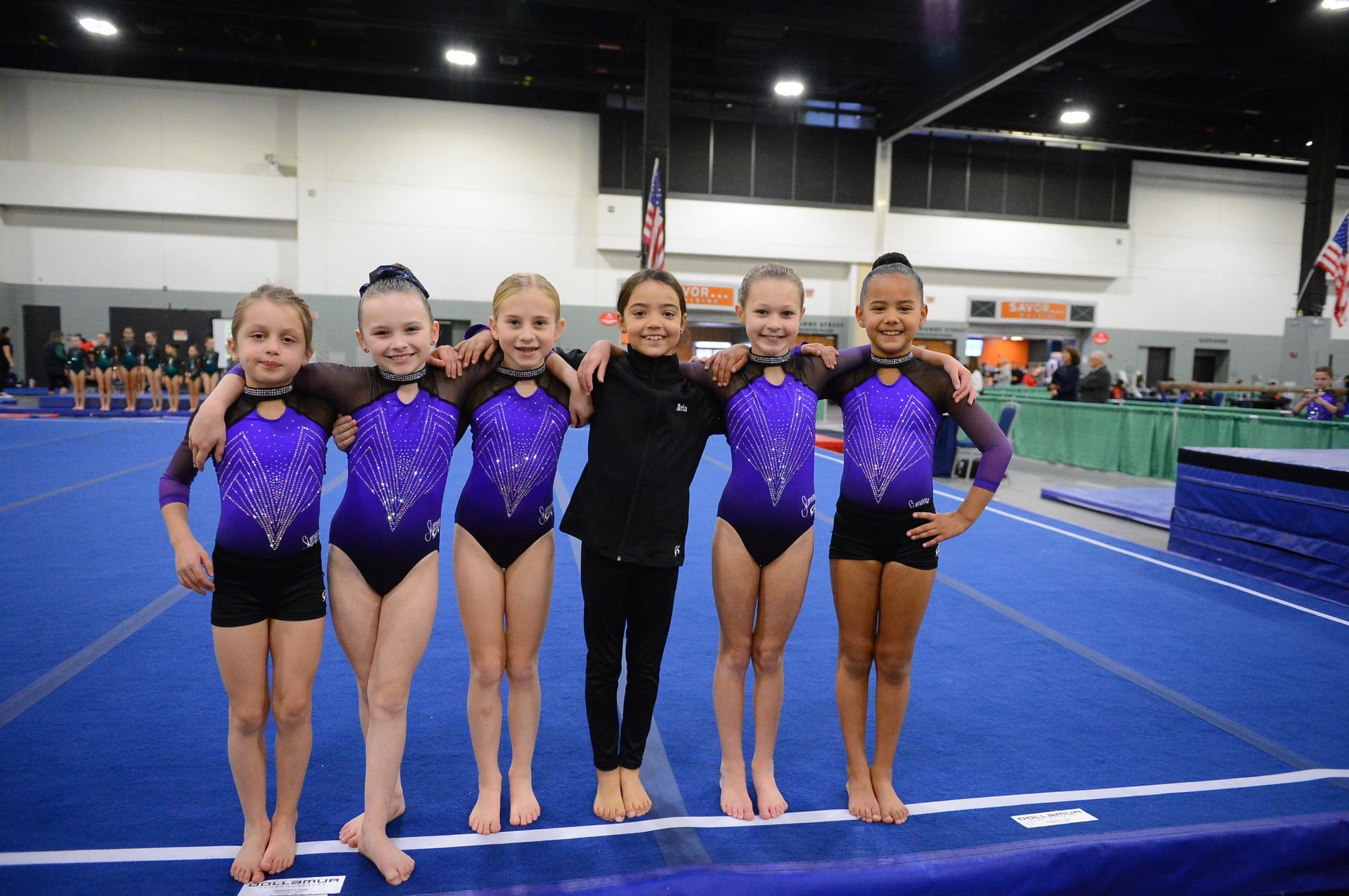A group of young girls are posing for a picture in a gym.