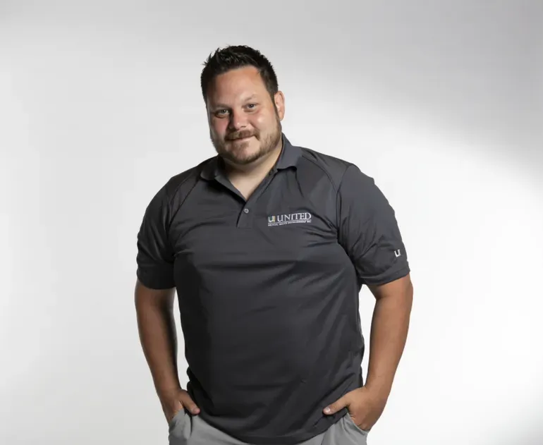 A man with a beard is wearing a black polo shirt
