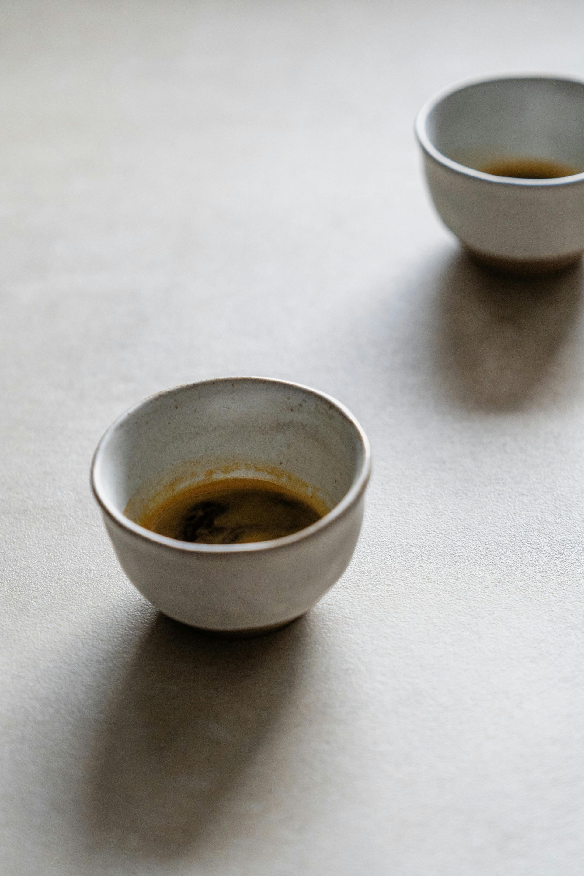 Hay dos pequeños tazones de café sobre una mesa.