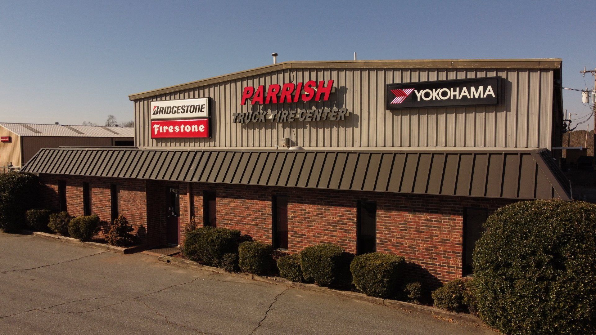 Parrish Automotive storefront with brick facade, metal roof, and tire brand signs.
