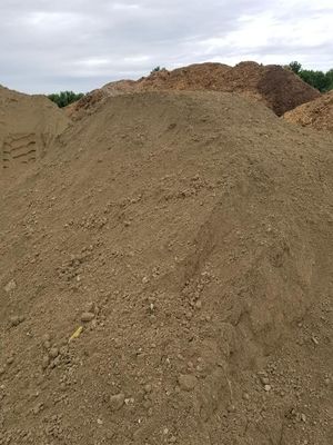 Large dirt mound at a construction or excavation site under a cloudy sky.