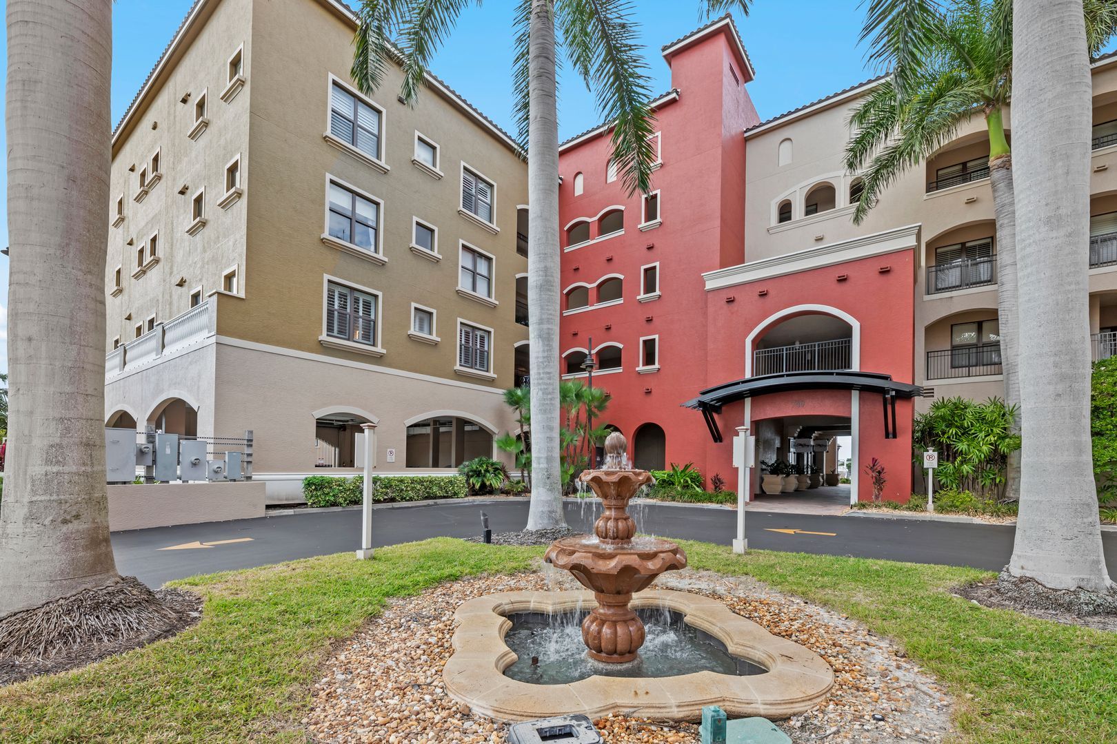 Courtyard with a fountain in front of colorful apartment buildings and palm trees
