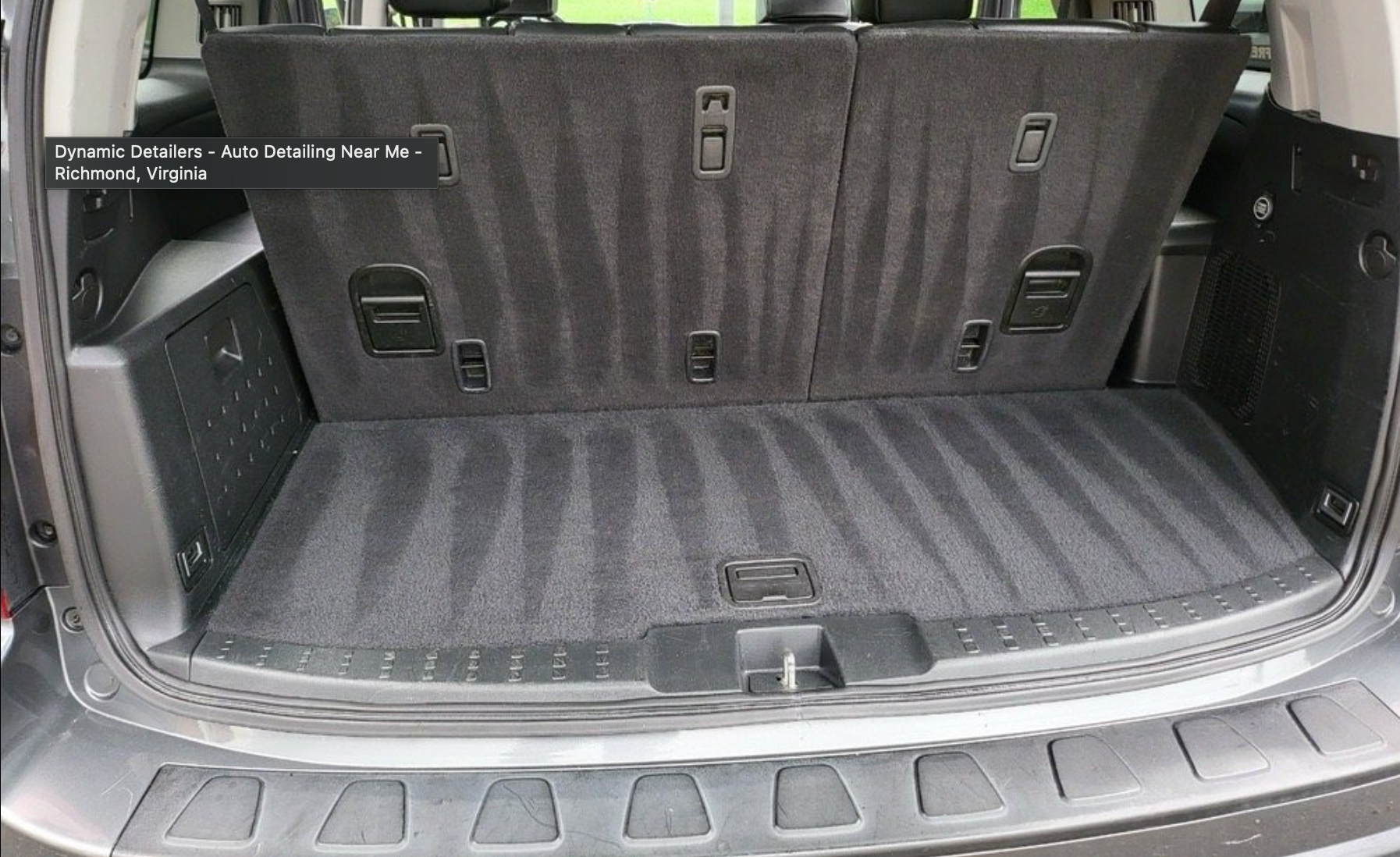 A close-up view of a clean, carpeted trunk space of a vehicle with the rear seats folded upright.