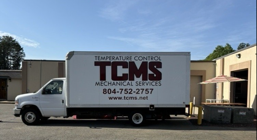 A white box truck parked in front of a commercial building, labeled 