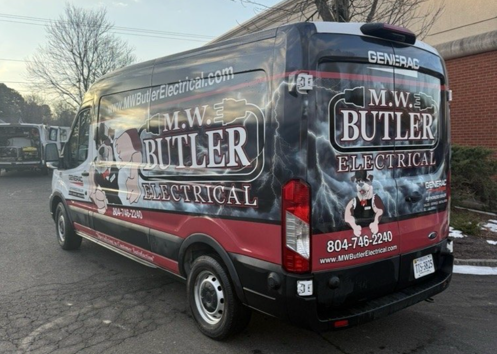 Black and red M.W. Butler Electrical utility van parked in a lot, featuring company logo, contact info, and dog mascot.