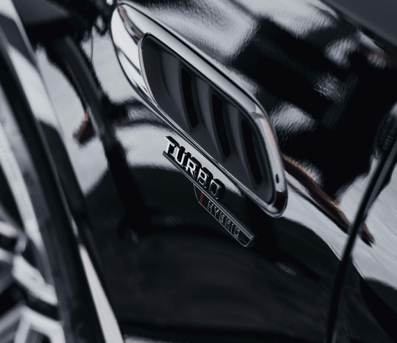 Close-up of a glossy black car fender with a chrome-trimmed side vent and a 
