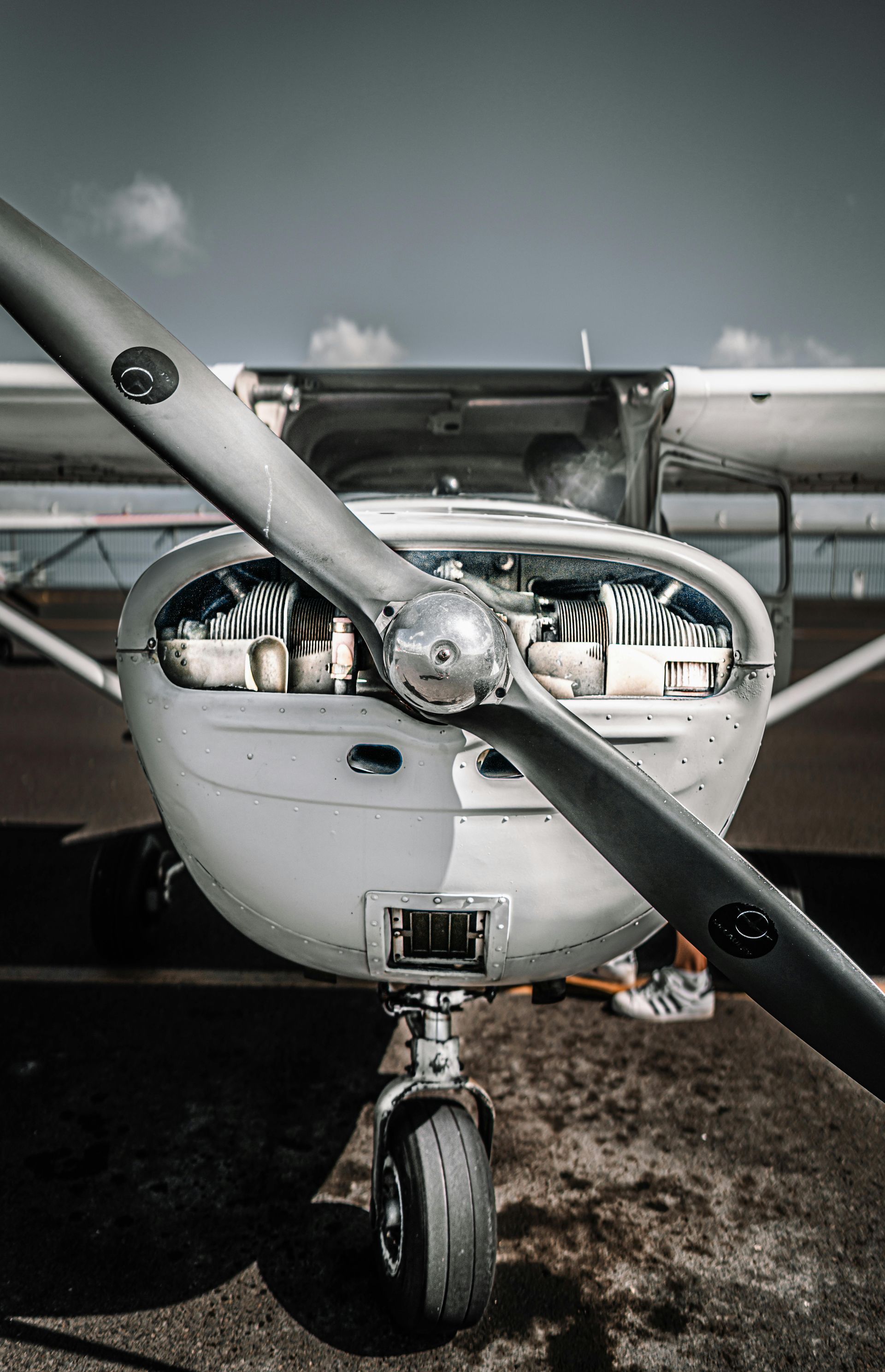 A close-up, front-facing view of a small propeller plane on the ground with its engine cowling removed.