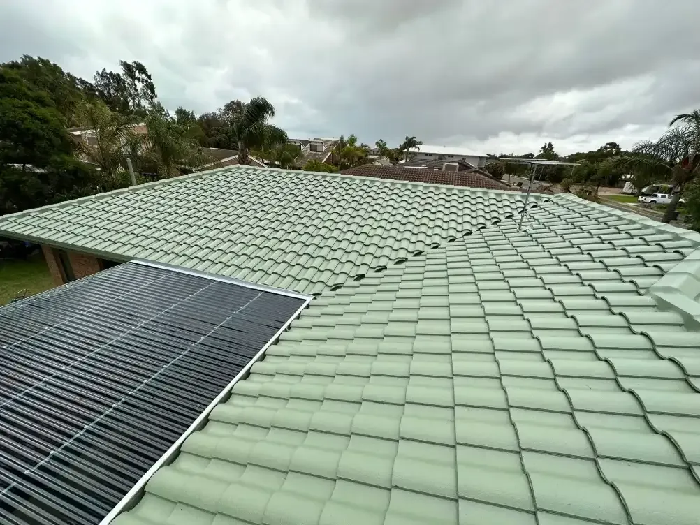 A green tiled roof with a solar panel on it