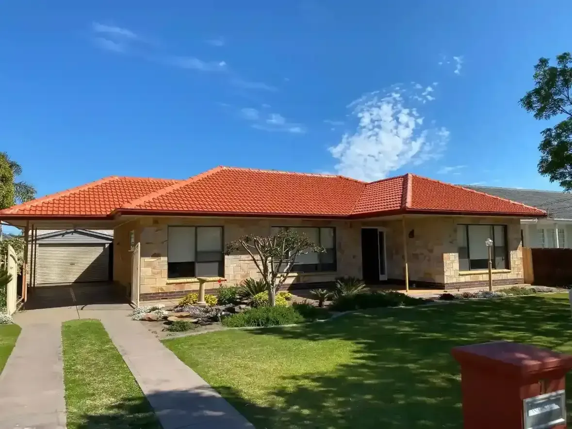 A house with a red tiled roof and a mailbox in front of it.