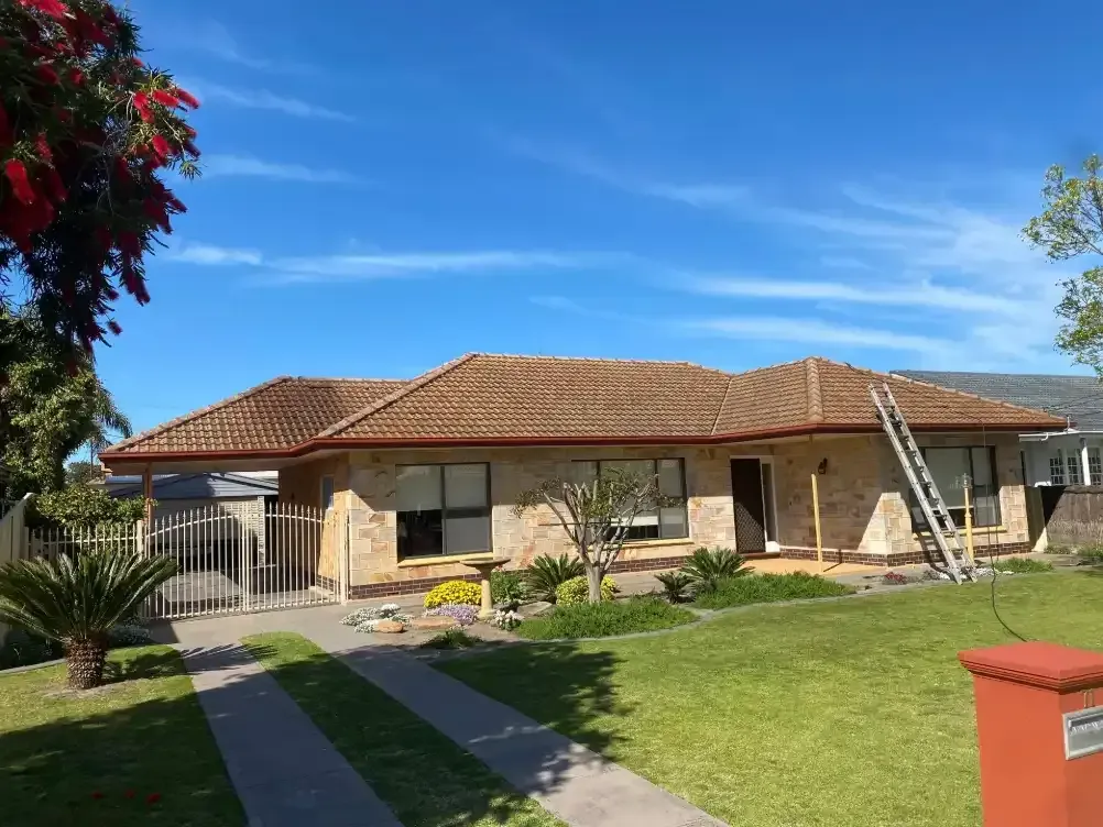 A large house with a tiled roof and a ladder in front of it.