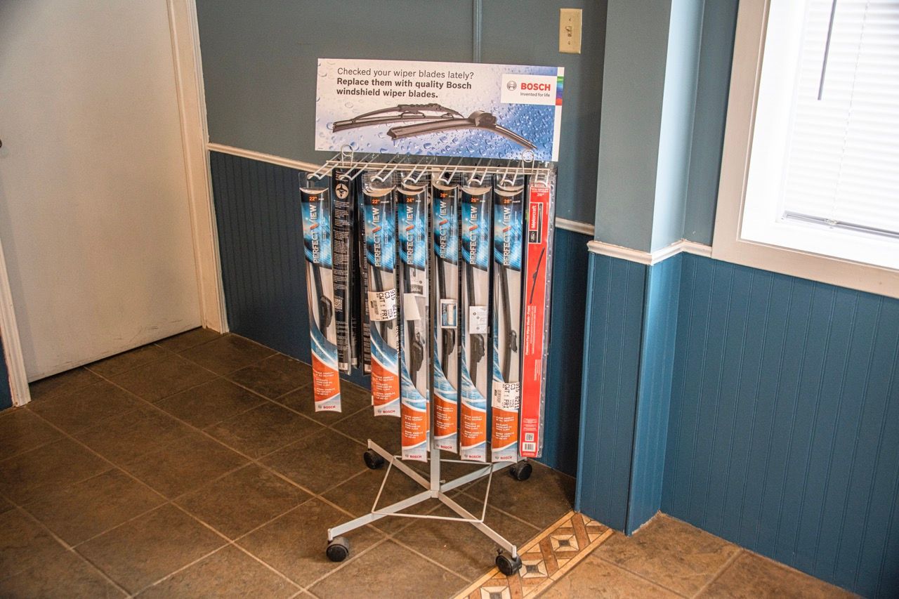 Display rack with multiple windshield wipers, set on a tiled floor, by a blue wall and a doorway | Jackson, MI