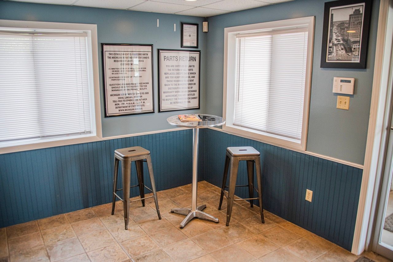 Interior with two windows, a small table, two stools, and framed menus on a blue wall | Jackson, MI