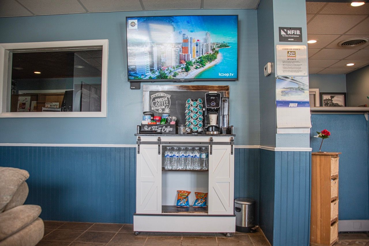 Coffee station with TV above, in a waiting area with blue walls, and a window | Jackson, MI