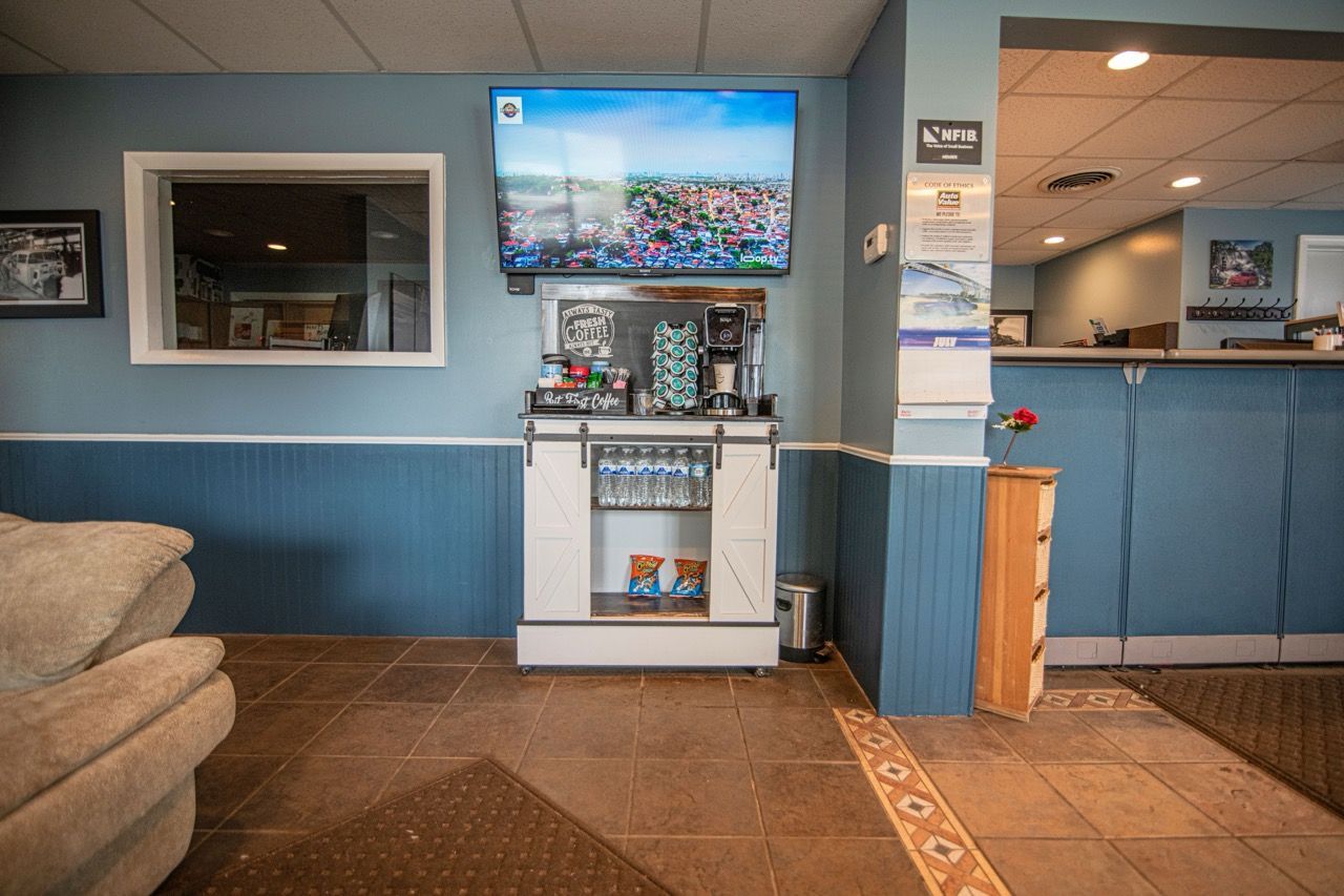 Waiting room with blue walls, TV, coffee station, and tan tile floor | Jackson, MI