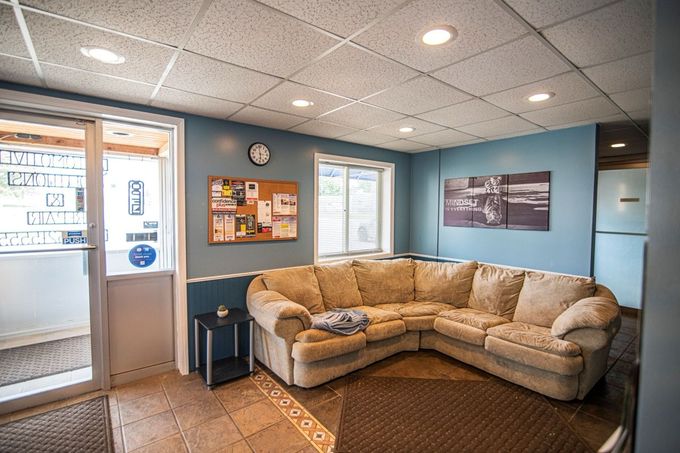 L-shaped beige couch in a room with blue walls, tile floor, door to outside, and a bulletin board | Jackson, MI