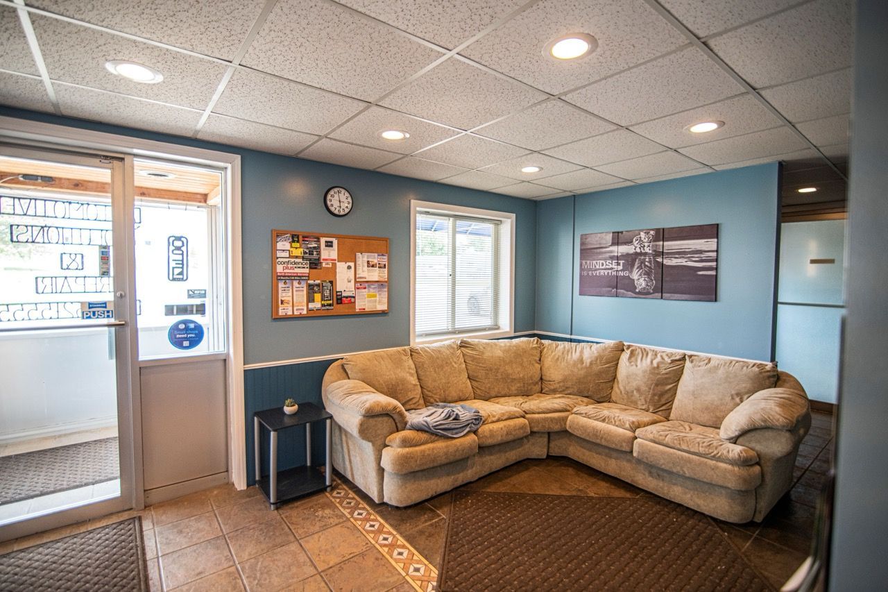 L-shaped beige couch in a room with blue walls, a bulletin board, and a glass door | Jackson, MI