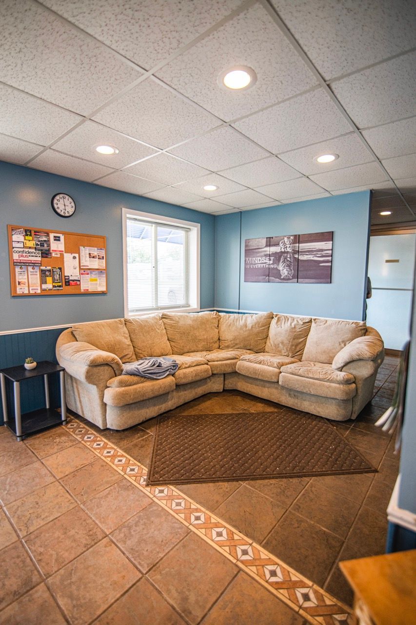 L-shaped beige couch in a room with blue walls, tiled floor, and a window | Jackson, MI