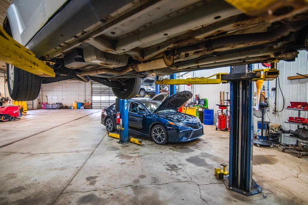 Cars on lifts in a mechanic shop. One car's hood is open. Tools and equipment are visible | Jackson, MI