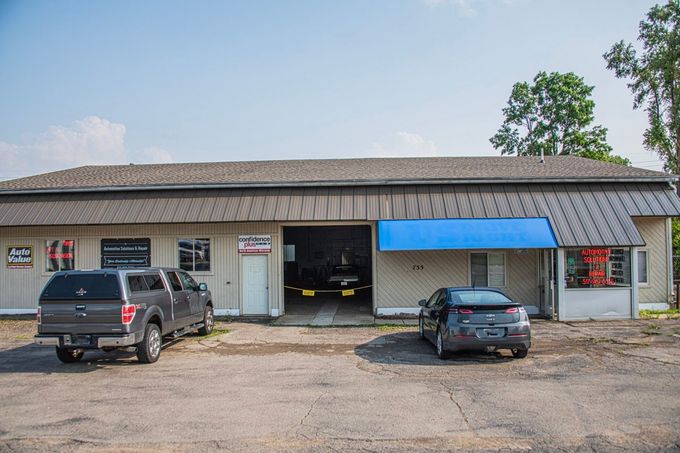 A car repair shop with a truck and a sedan parked outside, sunny day | Jackson, MI