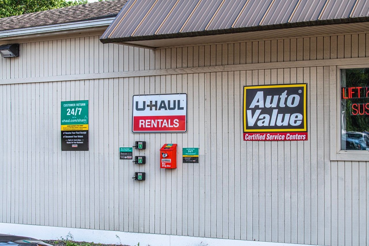 Exterior of a business with U-Haul Rentals and Auto Value signs on a white paneled building | Jackson, MI