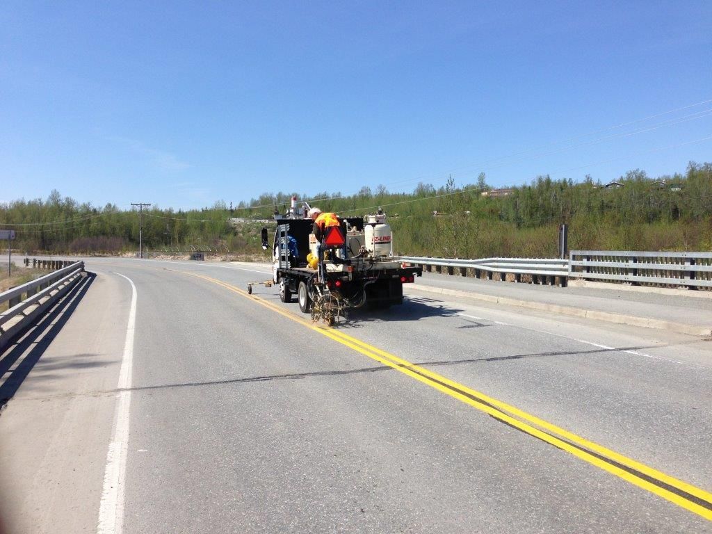 Road crew repairing a rural highway, with workers on a truck over the center line.