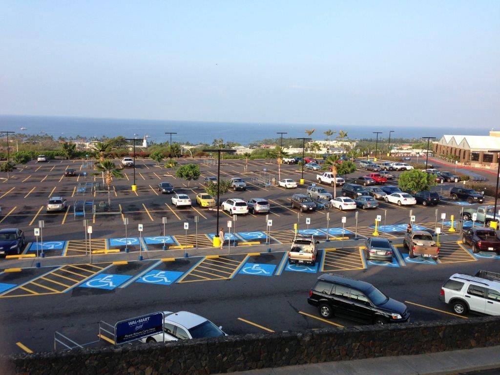 Busy coastal parking lot with many cars, accessible spaces, and ocean in the background