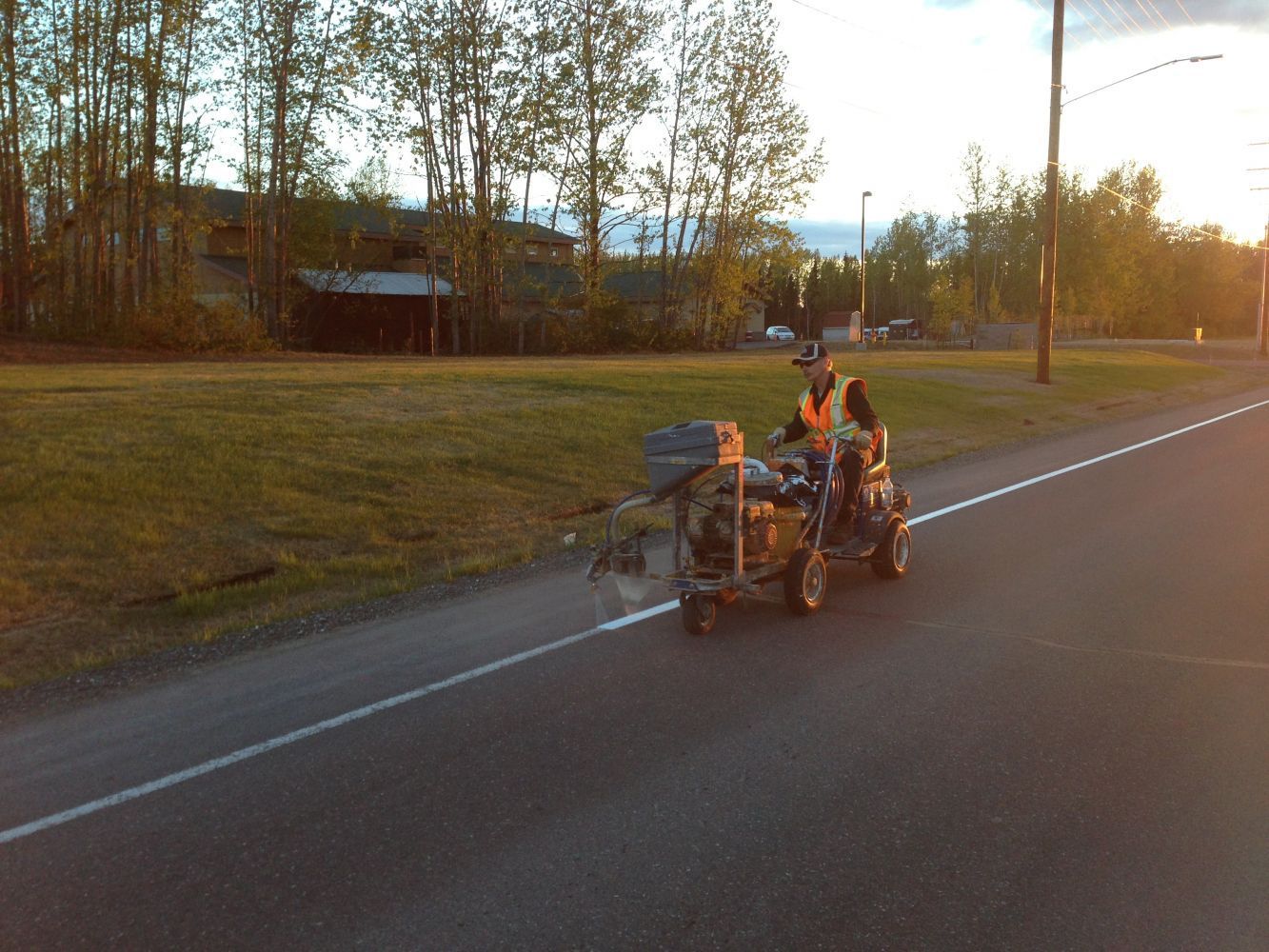 Two people on a cargo tricycle riding along a road at sunset