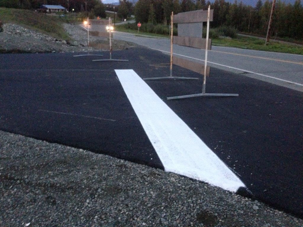 Roadwork sign and white painted lane marking on a dark asphalt road at dusk