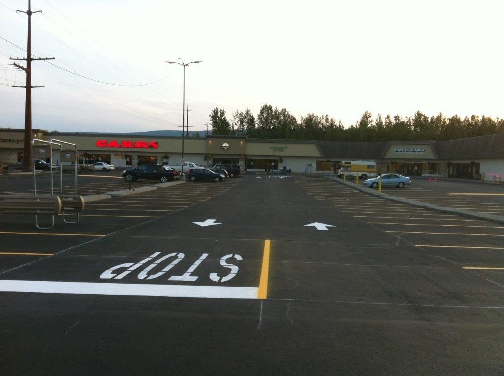 Empty parking lot with painted STOP marking and store front in the distance at dusk