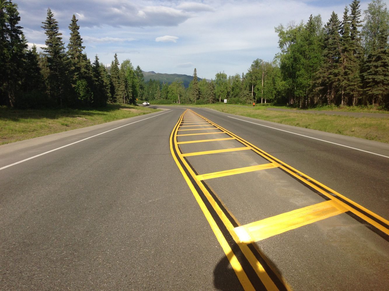 Empty highway with yellow lane markings stretching through a forested landscape