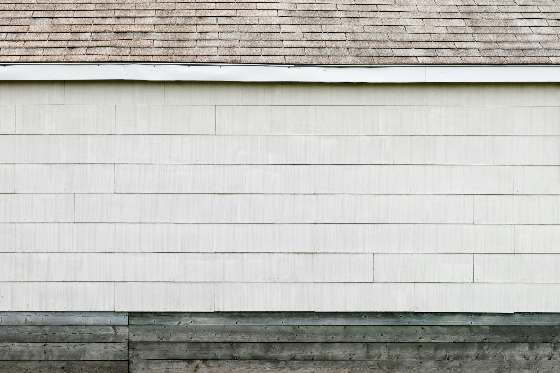 A man is installing a slate roof on a house.