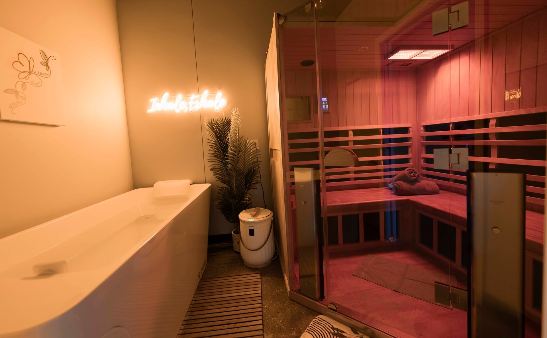 A man is laying in a bathtub next to a sauna.