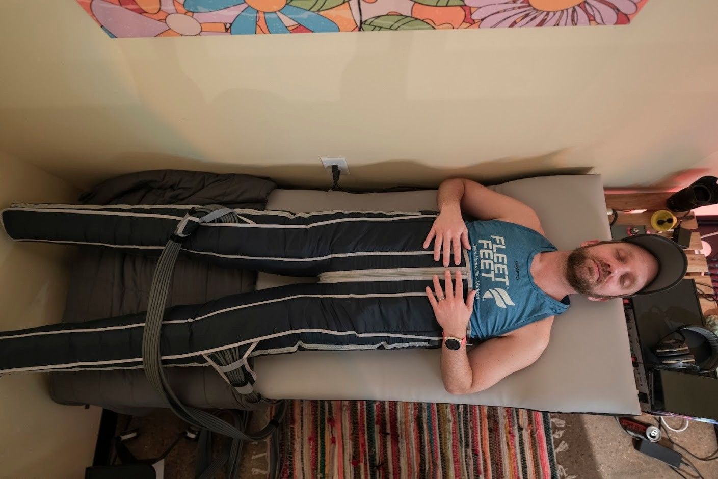 A man is laying on a bed with a compression device on his legs.