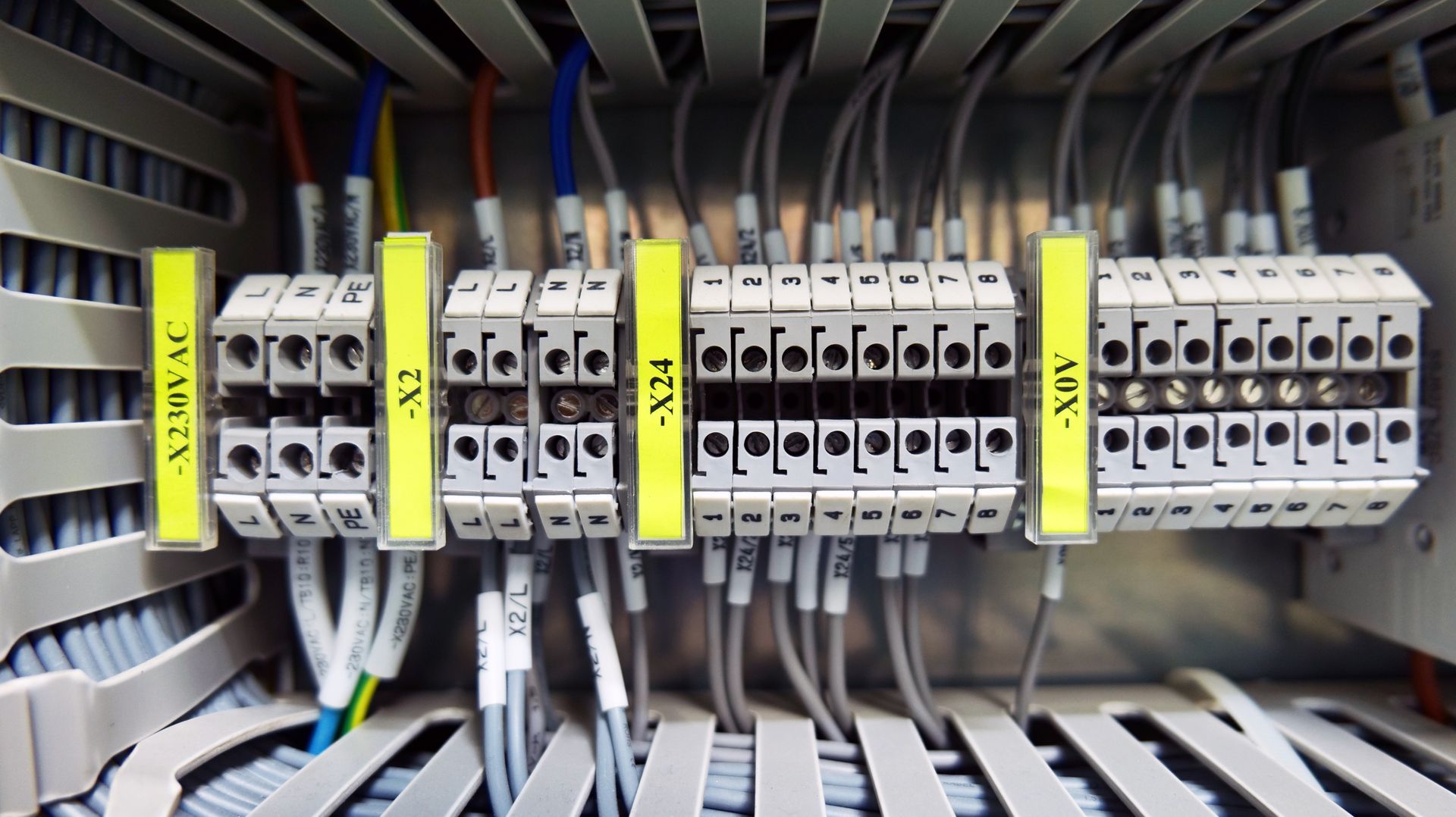 Row of electrical circuit breakers and wiring inside a control panel, with yellow safety tags.