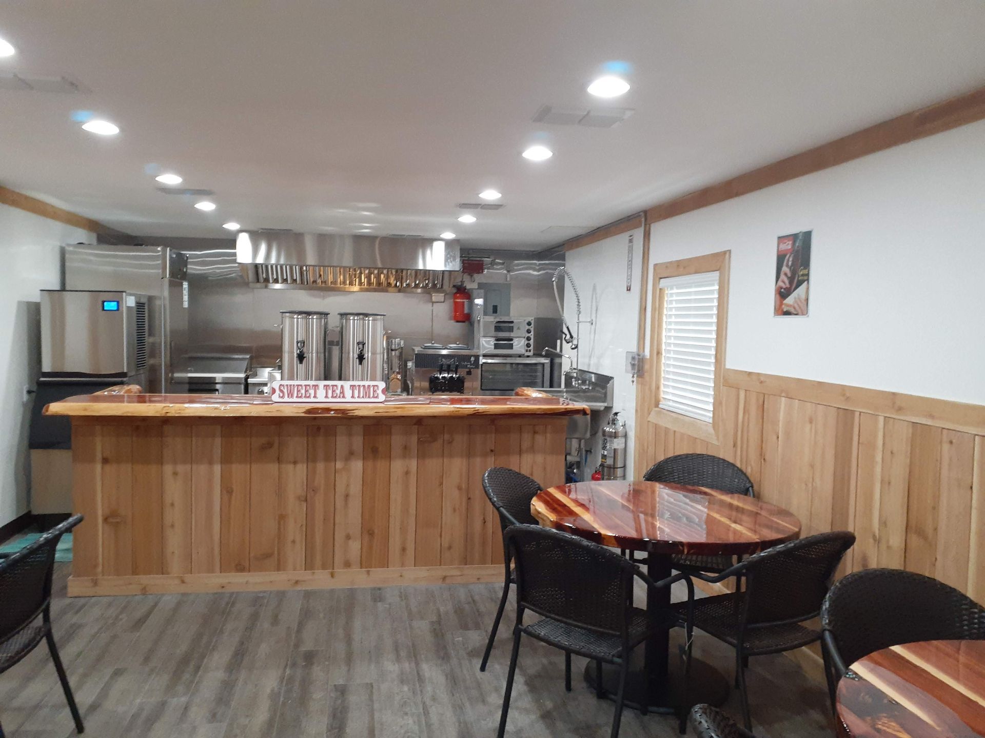 A restaurant with tables and chairs and a kitchen in the background.