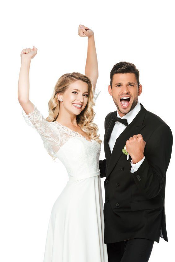 A bride and groom are celebrating their wedding with their fists in the air.