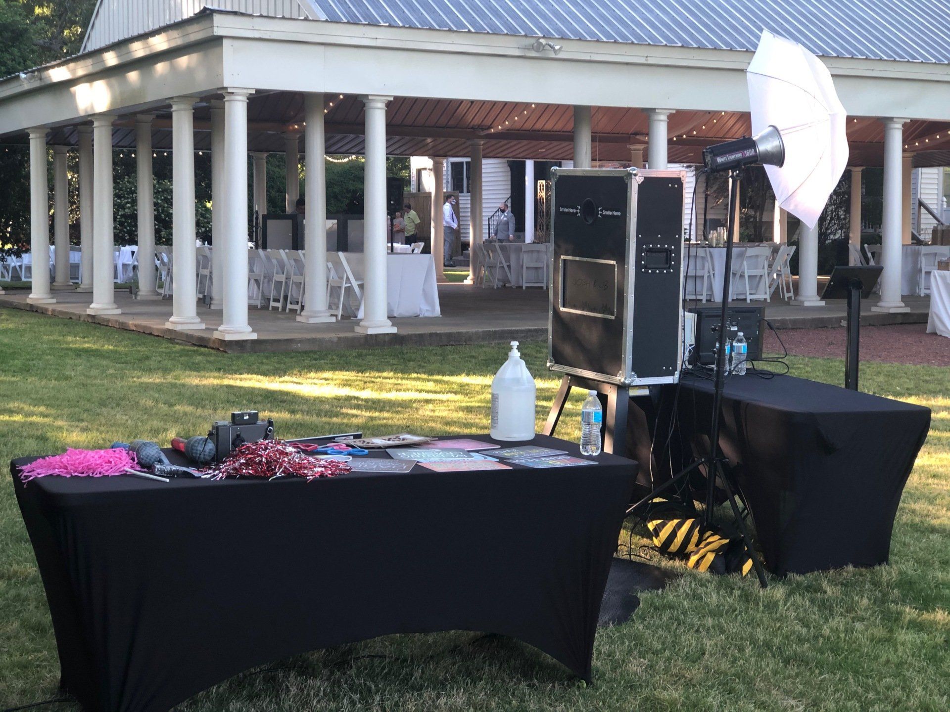 A photo booth is set up in the grass in front of a gazebo.