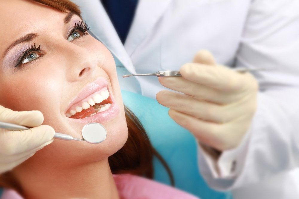 Woman Smiling During a Dental Exam; Dentist Using Tools and Wearing Gloves — Tamworth Orthocare In Tamworth, NSW