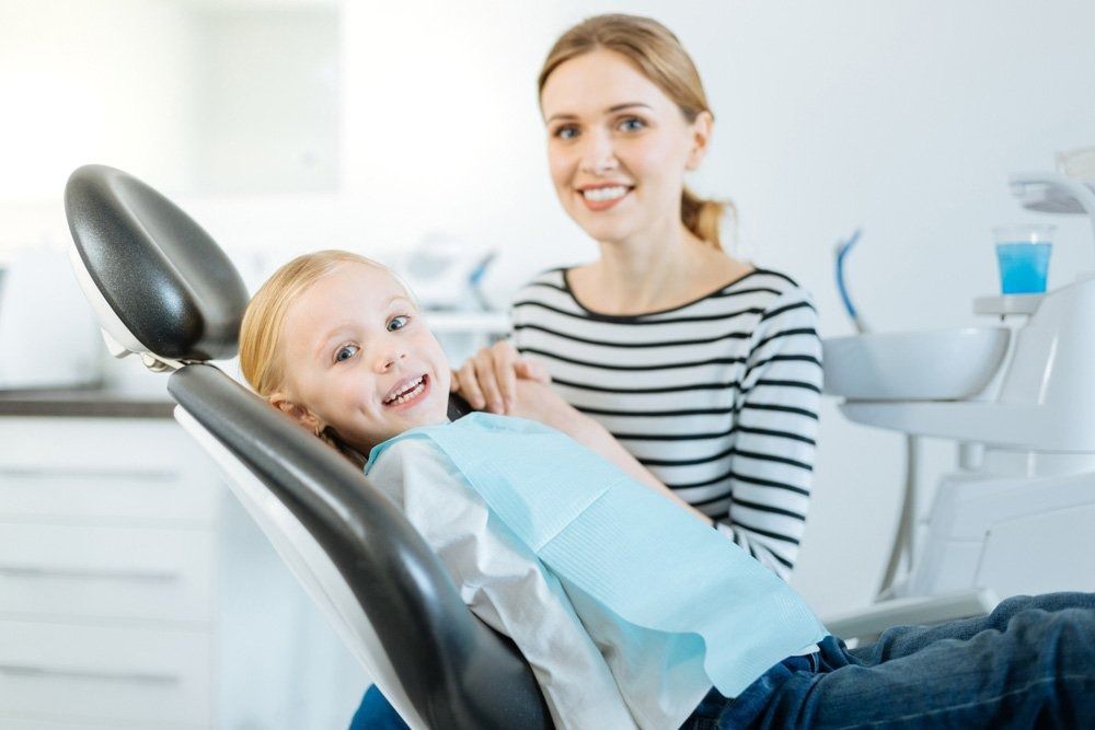 Girl Smiles in Dentist Chair With Mother Present. Dental Office Setting — Tamworth Orthocare In Tamworth, NSW
