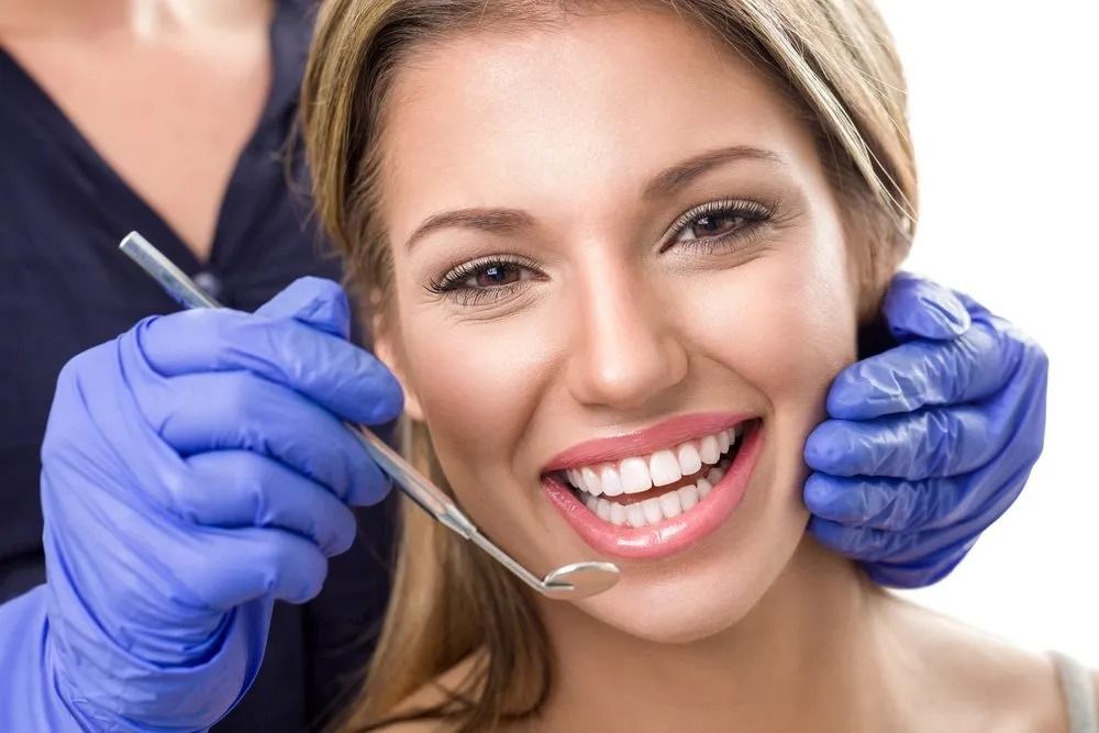 Woman Smiling During Dental Exam, Dentist Holding Mirror — Tamworth Orthocare In Muswellbrook, NSW