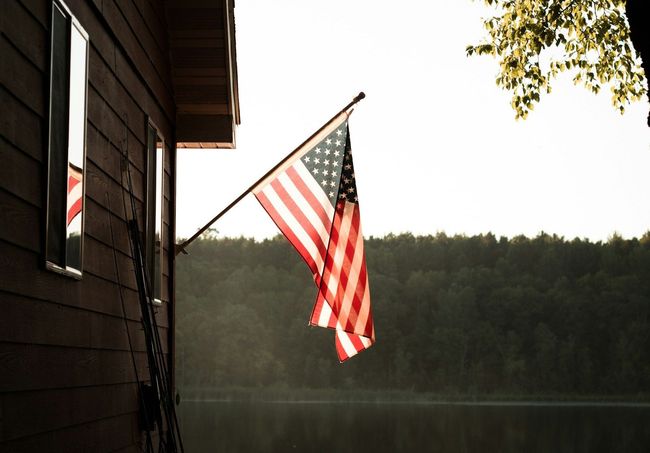 An american flag is hanging from the side of a house