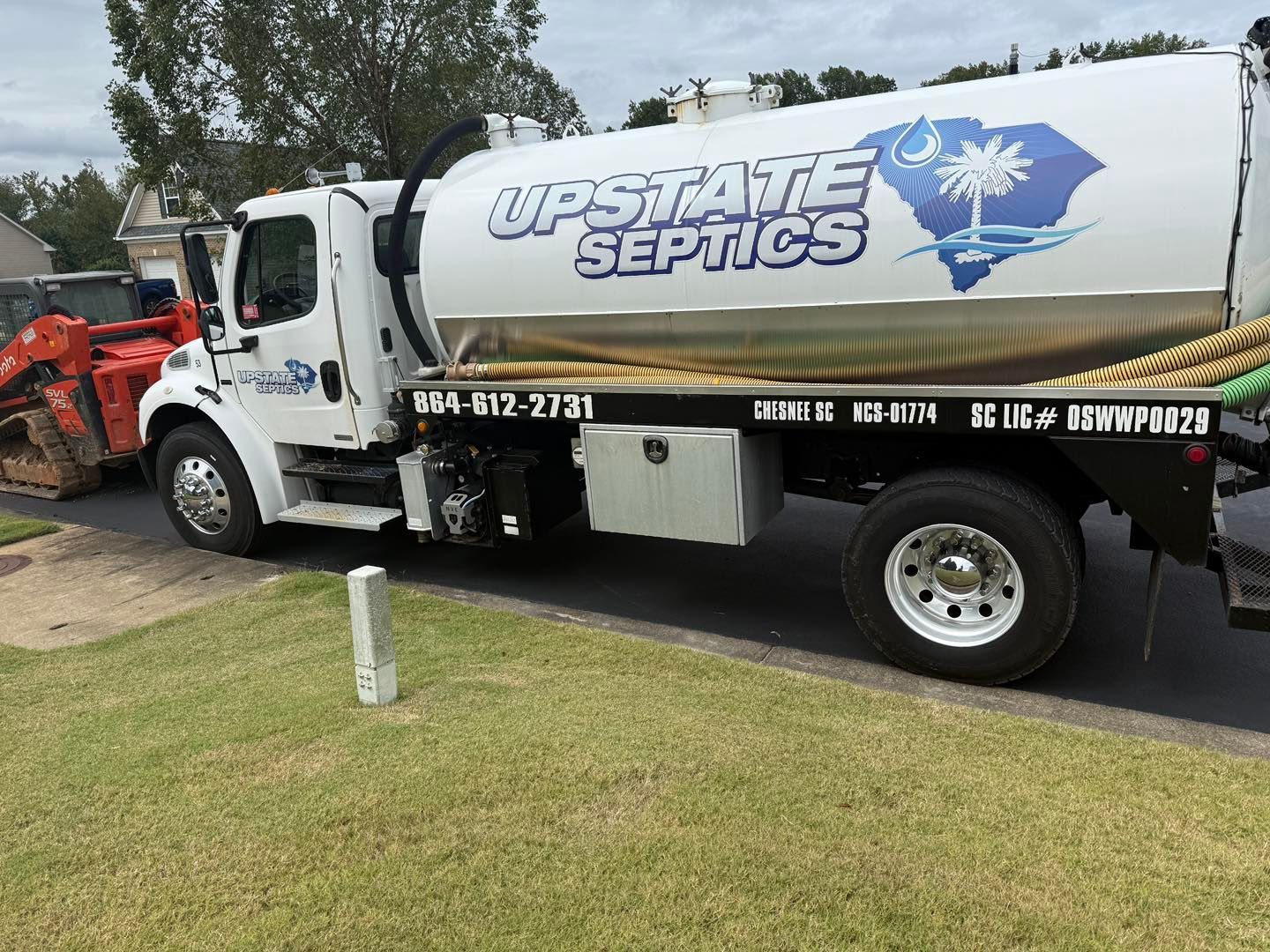 An Upstate Septics service truck with a South Carolina graphic on its tank parked on a residential street.