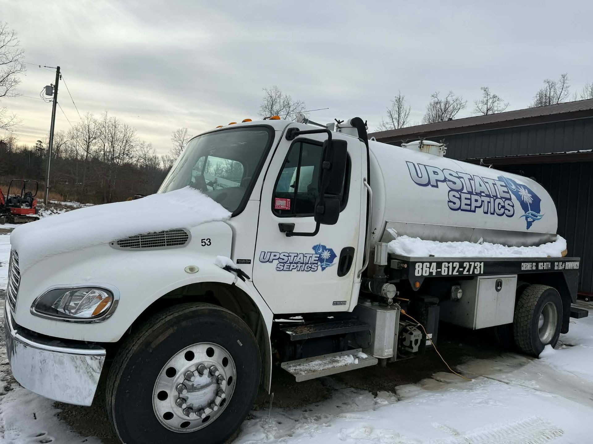 A white septic service truck parked outdoors in the snow, featuring the company name 