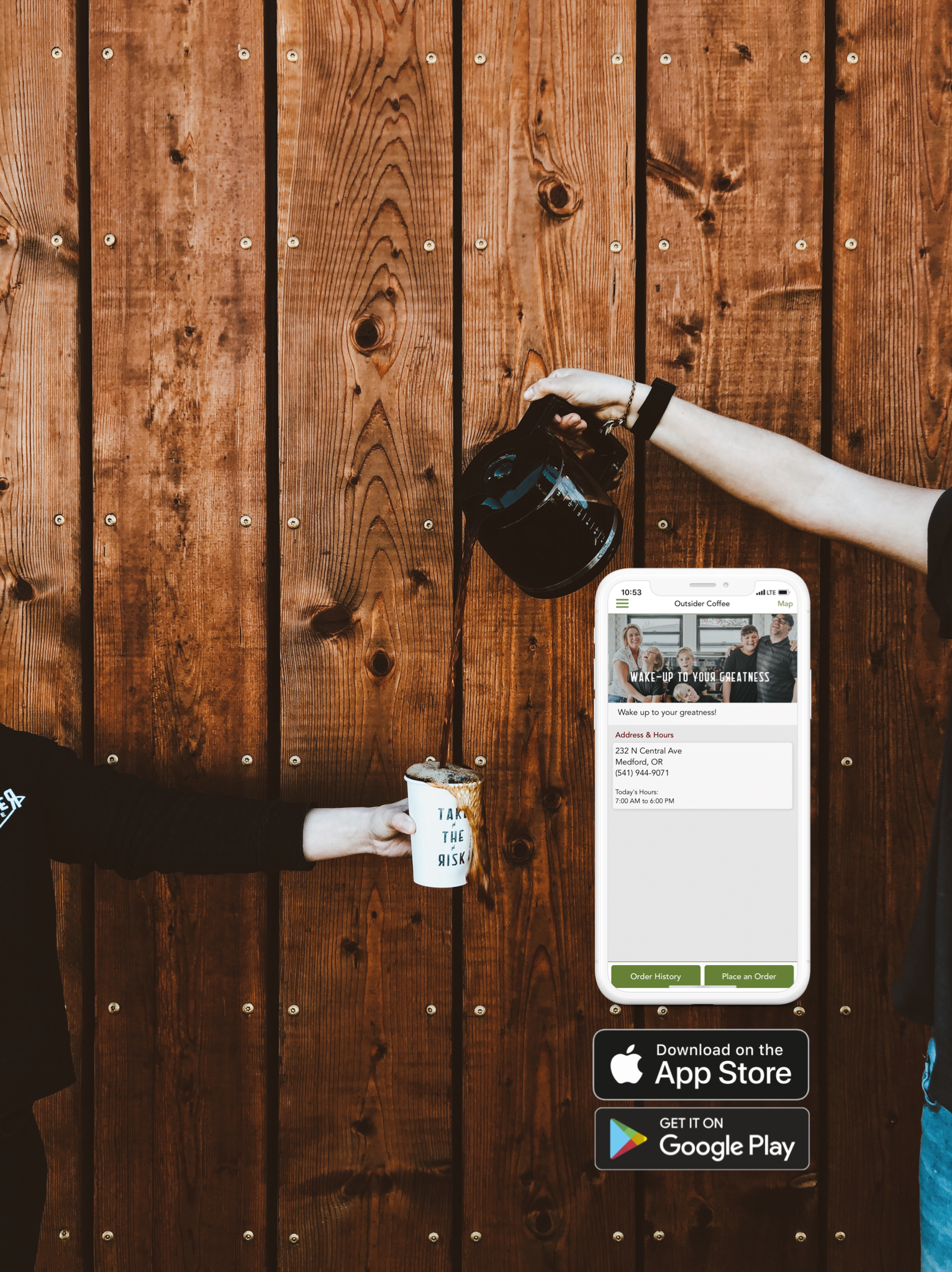 Hand pouring coffee into a mug beside a smartphone app screen against a wooden wall