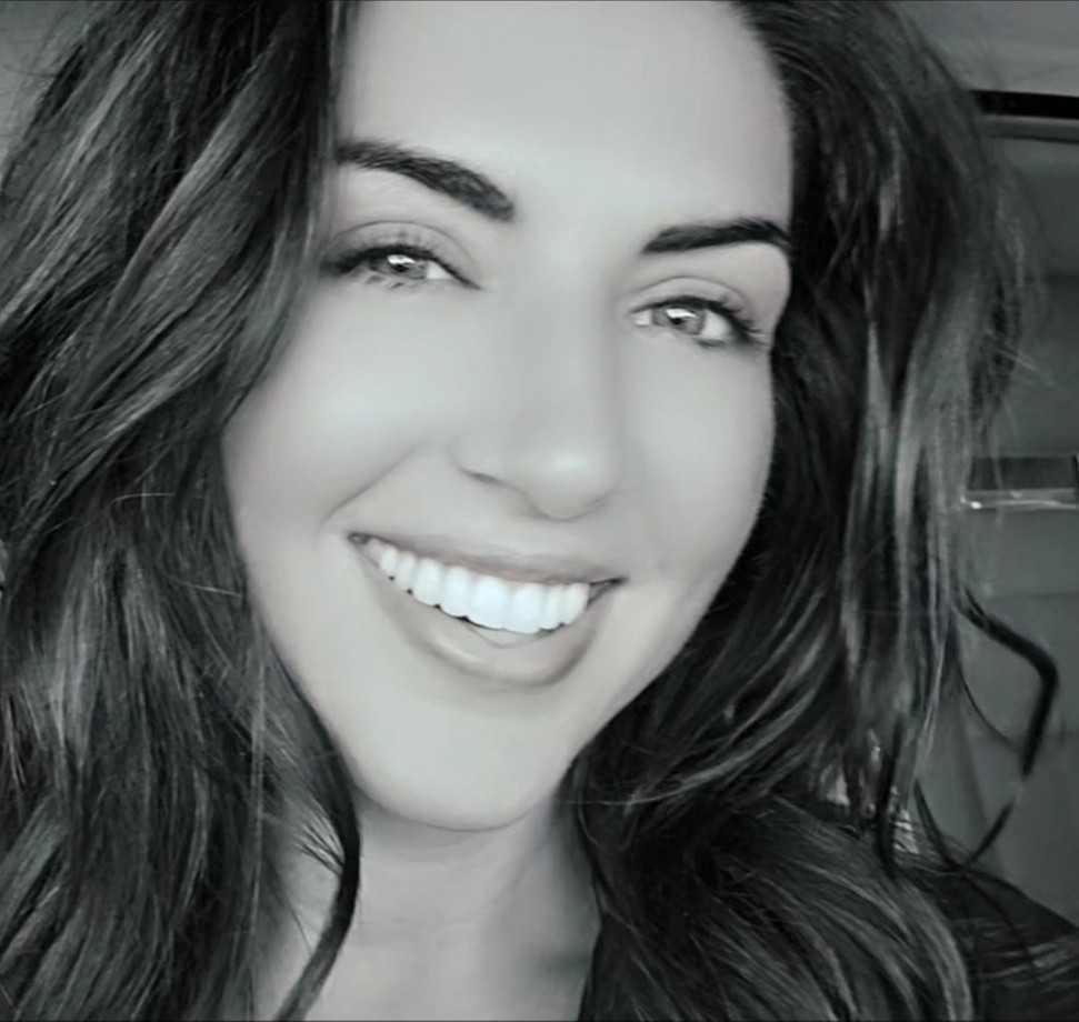 Smiling woman with dark wavy hair in a black-and-white portrait