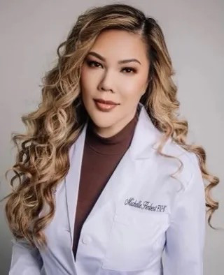 Professional woman in a white lab coat posing against a gray studio background.