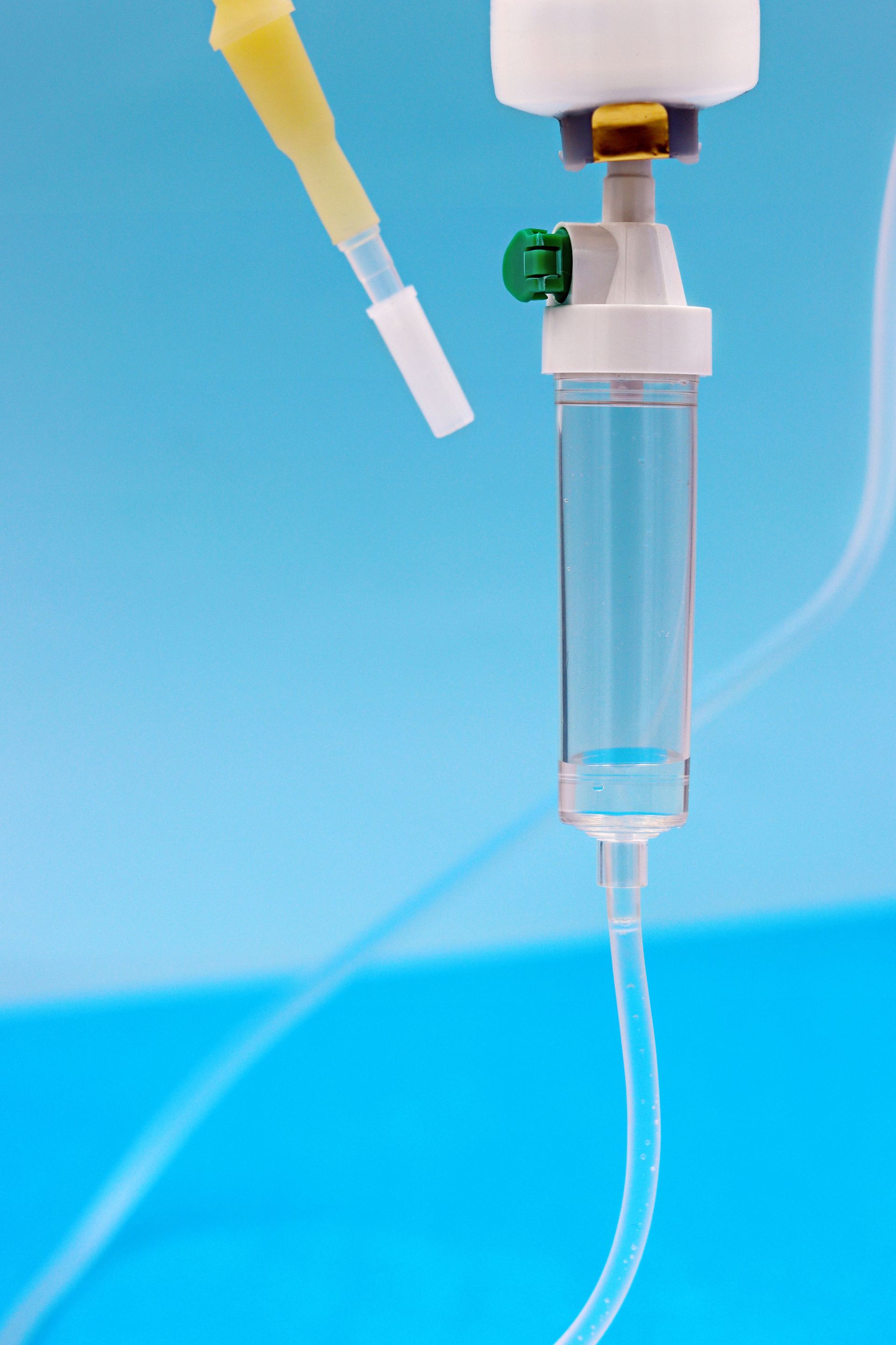 Clear IV drip chamber with tube against a blue background