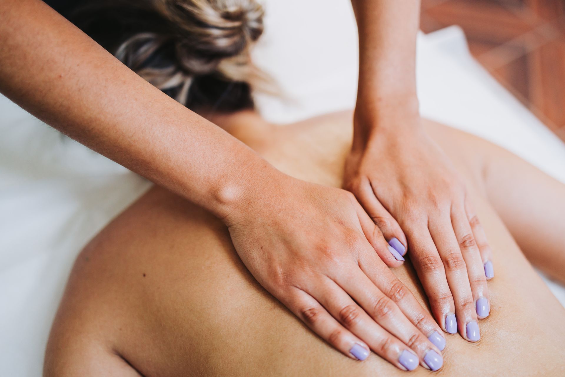 Hands massaging a person’s bare back during a spa treatment.
