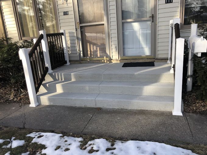 A porch with stairs and a railing in front of a house